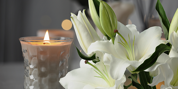 A serene arrangement of white flowers in a vase with a candle, representing comfort for Sympathy P.R.E.P.